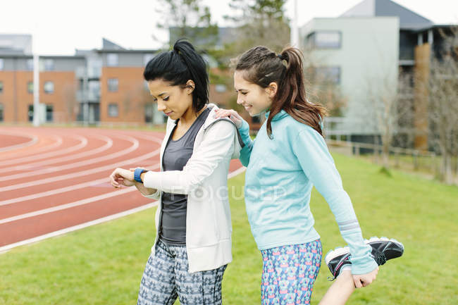Dos mujeres jóvenes al aire libre, haciendo ejercicio, estirándose - foto de stock