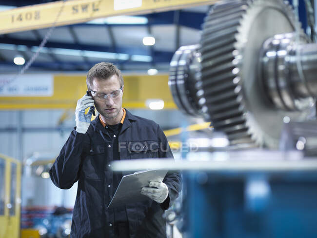 Engineer using mobile phone in engineering factory — Stock Photo