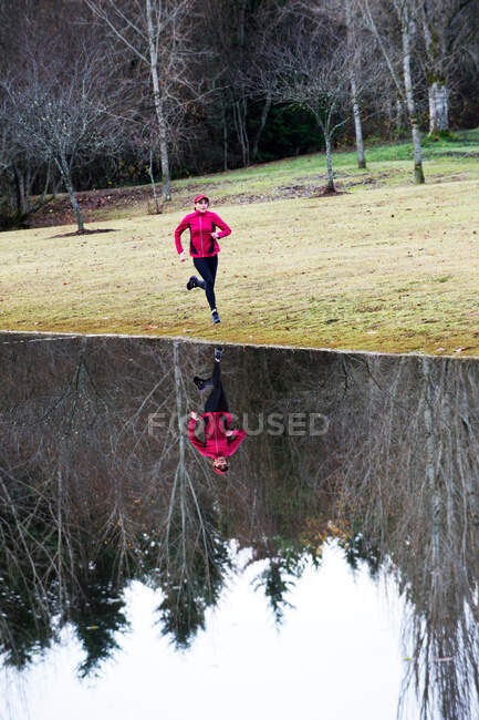 Mujer corriendo por lago aún rural - foto de stock