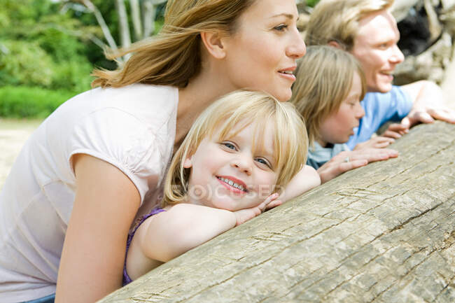 Family leaning on a log — Stock Photo