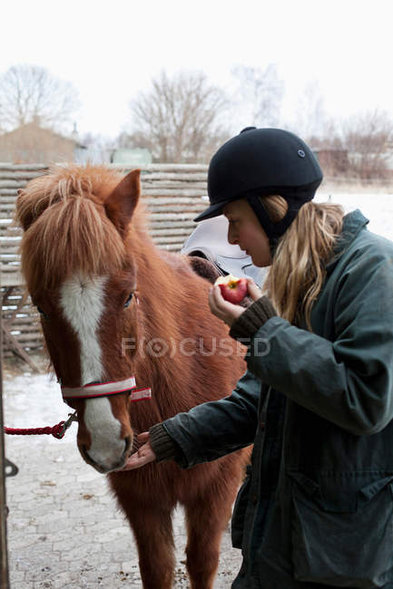 Mulher alimentando maçã a cavalo ao ar livre — Fotografia de Stock