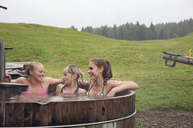 Три подружки сміються, коли відпочивають у сільській гарячій ванні (Саттельбергалм, Тіроль, Австрія). — стокове фото