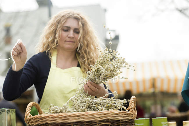 Commerciante di mercato con cesto di rami di ulivo — Foto stock