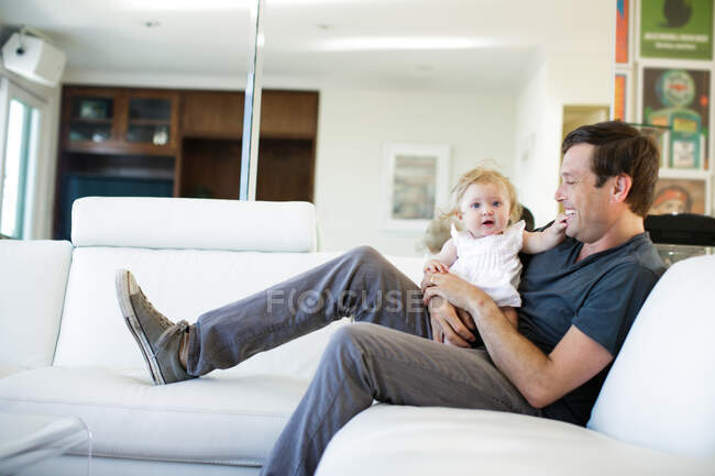 Baby girl sitting on father's lap — Stock Photo