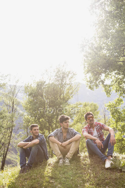 Tres jóvenes sentados en la hierba - foto de stock
