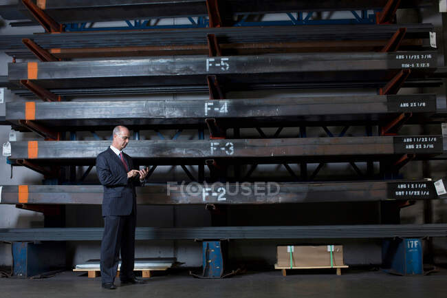 Homme d'affaires sur téléphone portable dans une usine de métal — Photo de stock