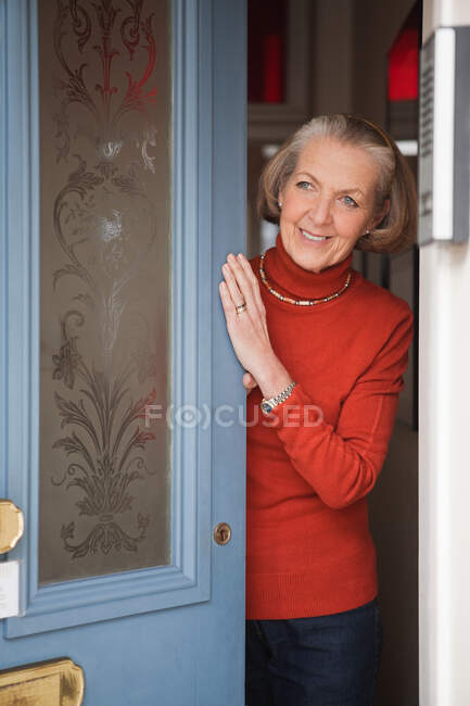 Mujer mayor abriendo la puerta principal - foto de stock