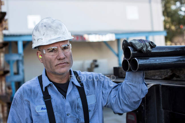 Businessman with pipes in metal plant — Stock Photo