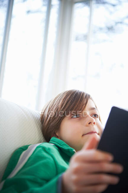 Хлопчик на дивані за допомогою цифрового планшета — стокове фото