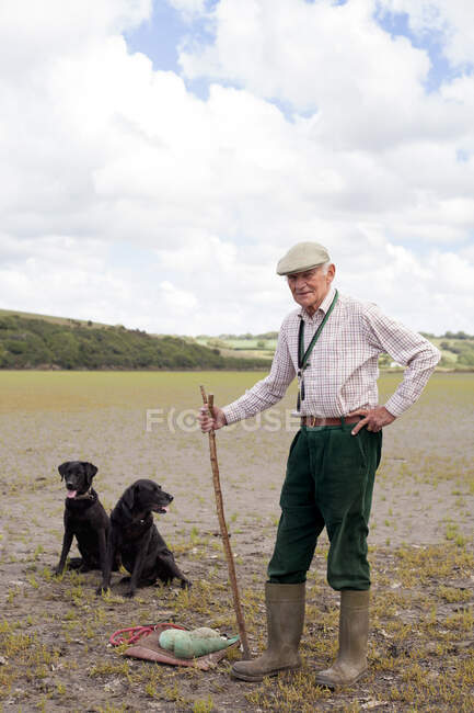 Retrato de hombre mayor con dos labradores negros - foto de stock