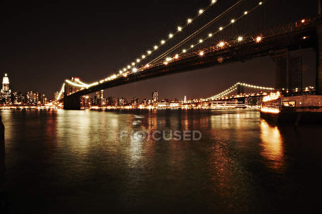 Manhattan buildings and bridge lit up at night — Stock Photo