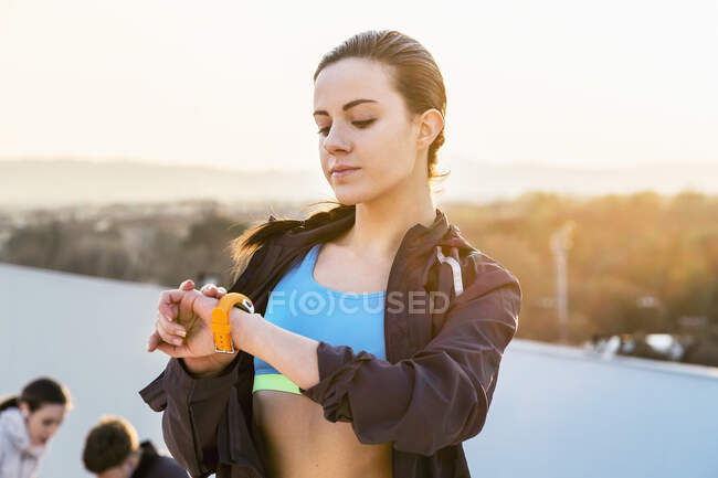 Mujer joven, al aire libre, mirando el rastreador de actividad - foto de stock