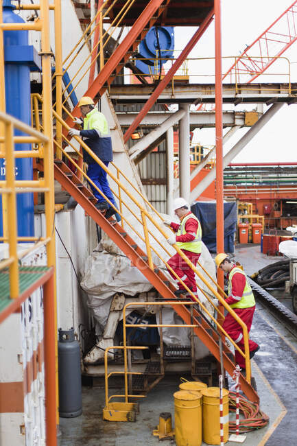 Рабочие поднимаются по лестнице на нефтяной вышке — стоковое фото