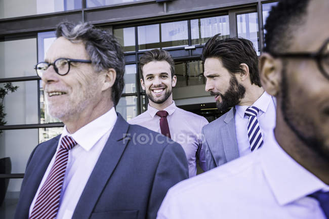 Businessmen talking whilst leaving office building — Stock Photo