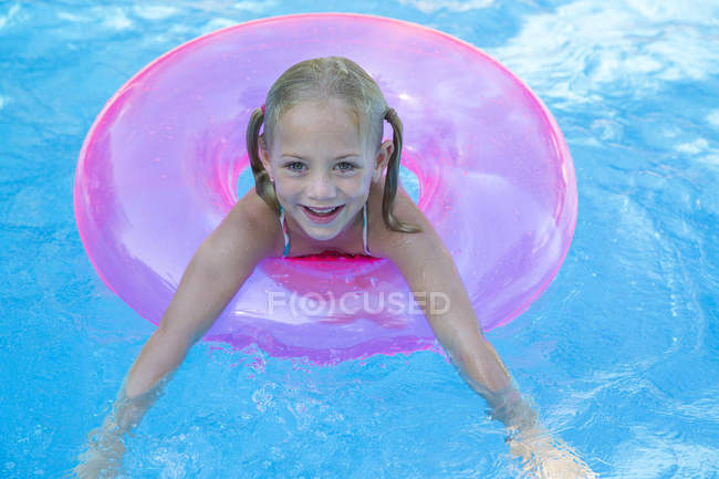 Portrait of girl in inflatable ring in garden swimming pool — Stock Photo