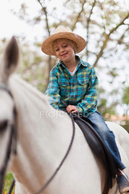 Усміхнений хлопчик верхи на коні в парку — стокове фото