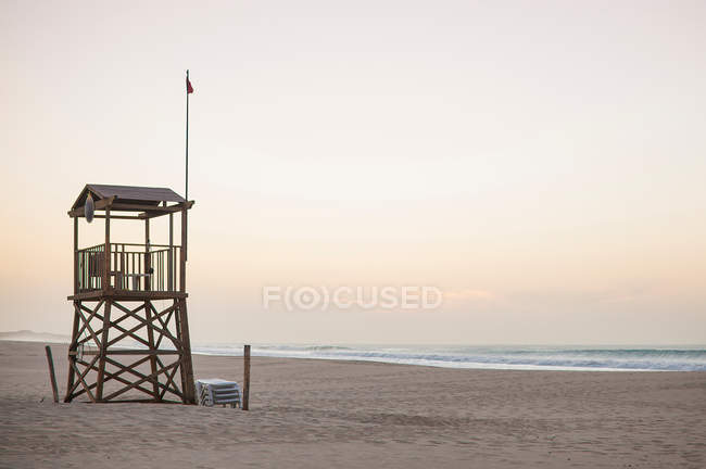 Tour de sauvetage sur la plage et ciel dégagé au coucher du soleil — Photo de stock