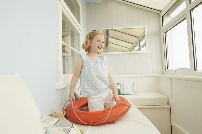 Menina brincando com cinto de vida no assento do apartamento de férias — Fotografia de Stock