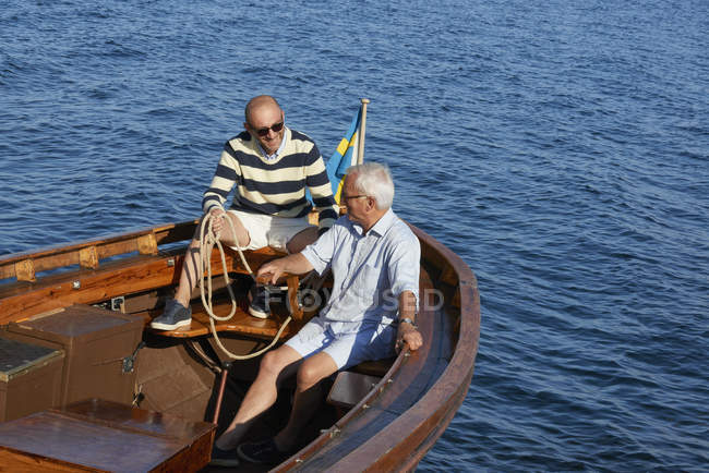 Друзья сидят в лодке в голубом океане — стоковое фото