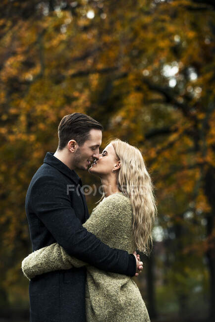 Jeune couple étreignant et embrassant dans les bois — Photo de stock