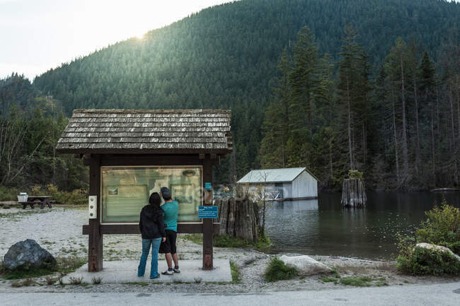 Coppia al cartello informativo, Buntzen Lake, British Columbia, Canada — Foto stock