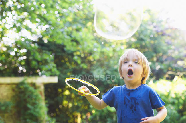 Menino fazendo bolha de grandes dimensões no quintal — Fotografia de Stock