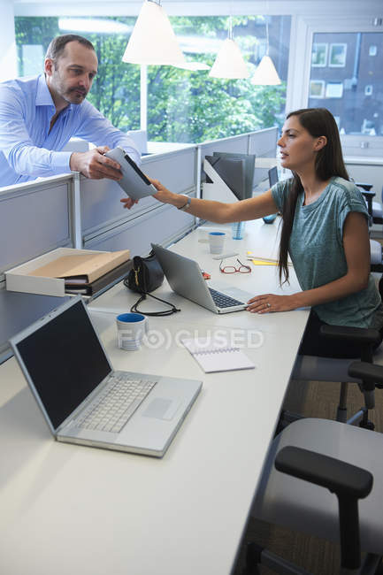 Man passing digital tablet over screen partition — Stock Photo