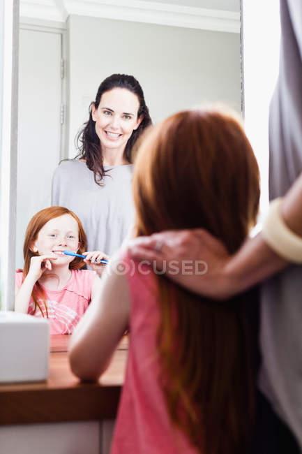 Mother watching daughter brush teeth — Stock Photo