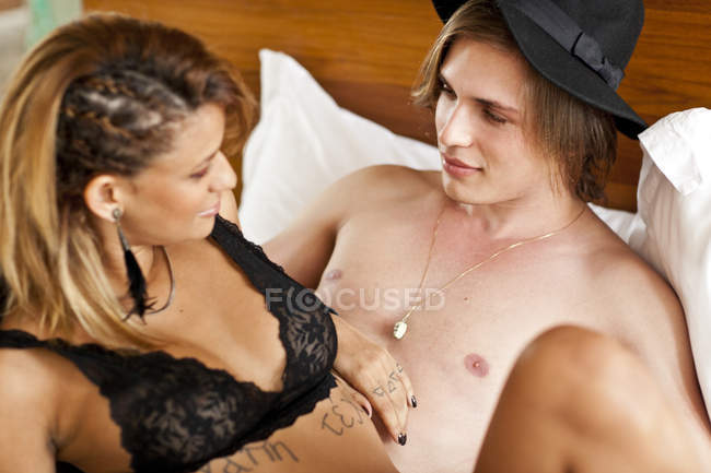 Casal jovem desvestido reclinado na cama do hotel — Fotografia de Stock