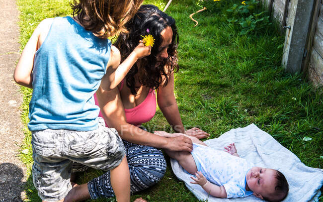 Boy jugando con la madre y el hermano bebé en el jardín - foto de stock