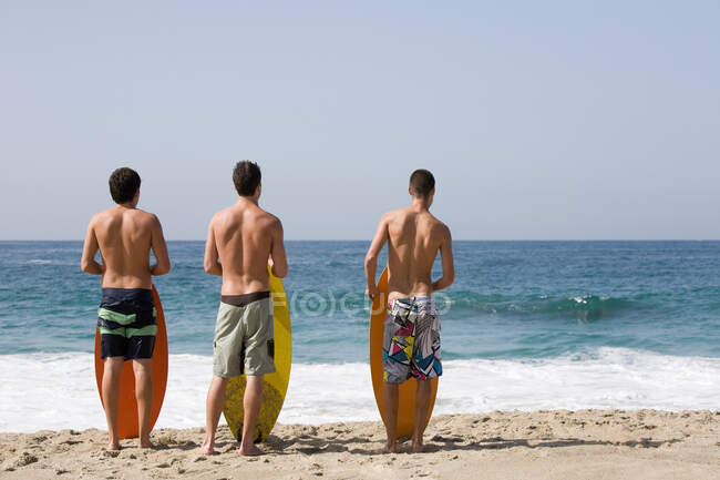 Três jovens na praia com pranchas de surf — Fotografia de Stock