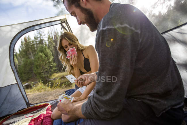 Jeune couple assis dans une tente jouant aux cartes, Lac Tahoe, Nevada, USA — Photo de stock