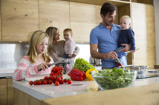 Fille avec la famille préparant des légumes frais dans la cuisine — Photo de stock