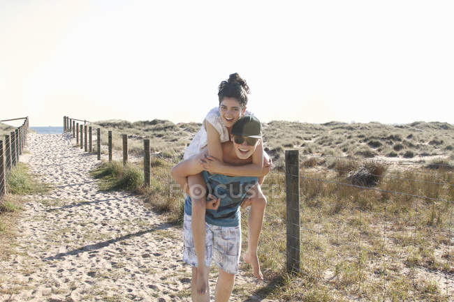 Hombre dando mujer joven a cuestas, Port Melbourne, Melbourne, Australia - foto de stock