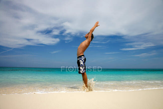 Man practicing yoga on tropical beach — Stock Photo