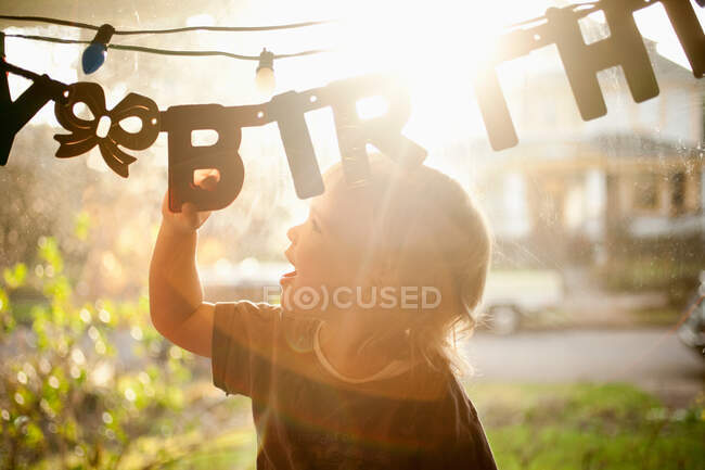 Giovane ragazzo toccando banner festa di compleanno — Foto stock