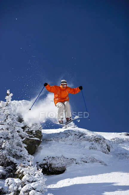 Esquiador masculino pulando na encosta — Fotografia de Stock