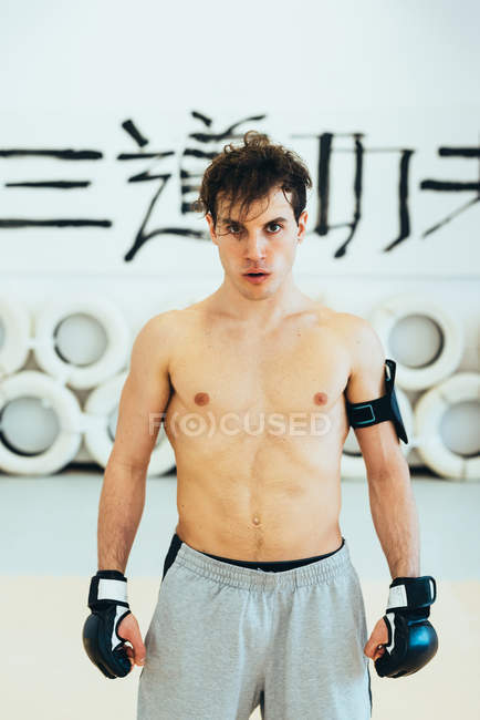 Homem no ginásio usando luvas de kickboxing e monitor de frequência cardíaca olhando para a câmera — Fotografia de Stock