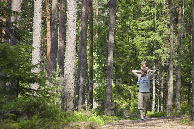 Padre spalla che porta il figlio del bambino attraverso la foresta, Somerniemi, Finlandia — Foto stock