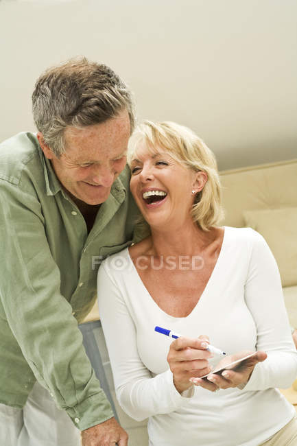Paar macht sich Notizen und lacht zu Hause — Stockfoto