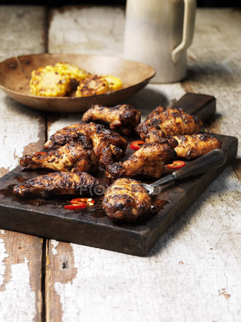 Barbecued peri peri chicken wings on wooden board — Stock Photo