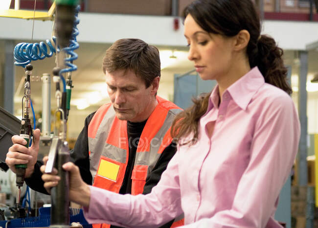 Mulher e homem trabalhando em máquinas na fábrica de componentes elétricos — Fotografia de Stock