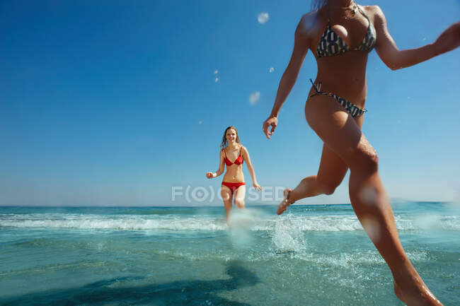 Two girls running out of the sea — Stock Photo