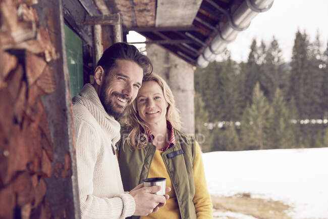 Retrato de casal em pé fora da cabine de madeira no inverno, Elmau, Baviera, Alemanha — Fotografia de Stock