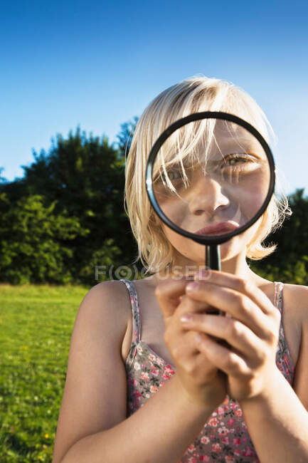 Girl playing with magnifying glass — Stock Photo