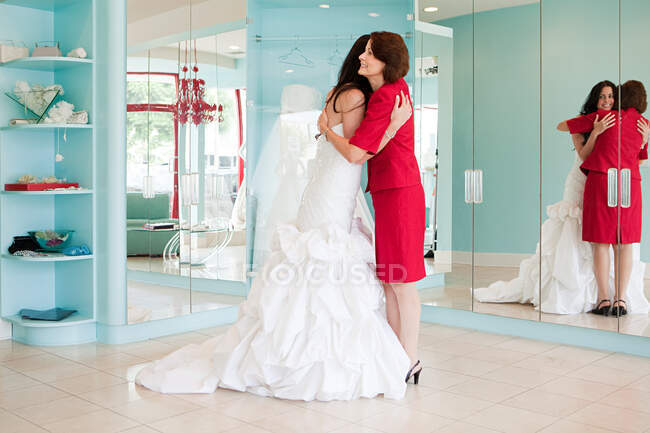 Tochter probiert Hochzeitskleid an, umarmt Mutter — Stockfoto