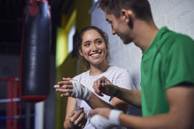 Young male and female boxers chatting while bandaging  hands — Stock Photo