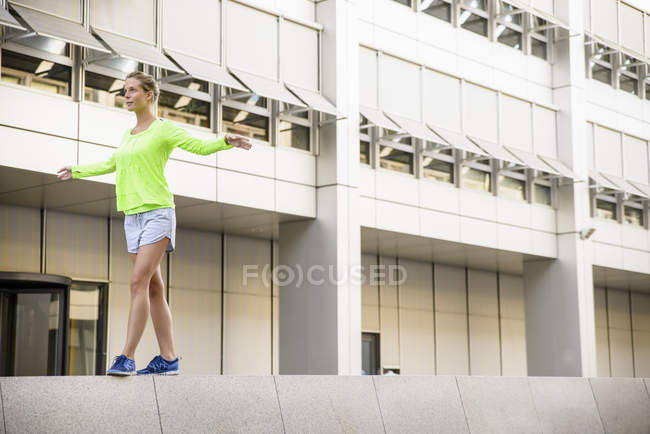 Mujer joven caminando en la pared - foto de stock