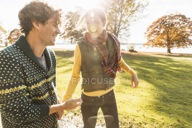 Пара сміється на сонячному світлі в парку — стокове фото