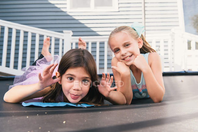 Meninas deitadas no trampolim, olhando para a câmera e fazendo rostos — Fotografia de Stock